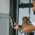 A man holds up a shirt in front of a mirror while also holding his phone