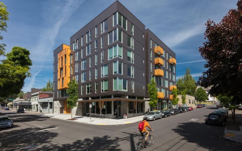 Find your perfect fit at Lower Burnside Lofts a person riding a bicycle on a street next to a building